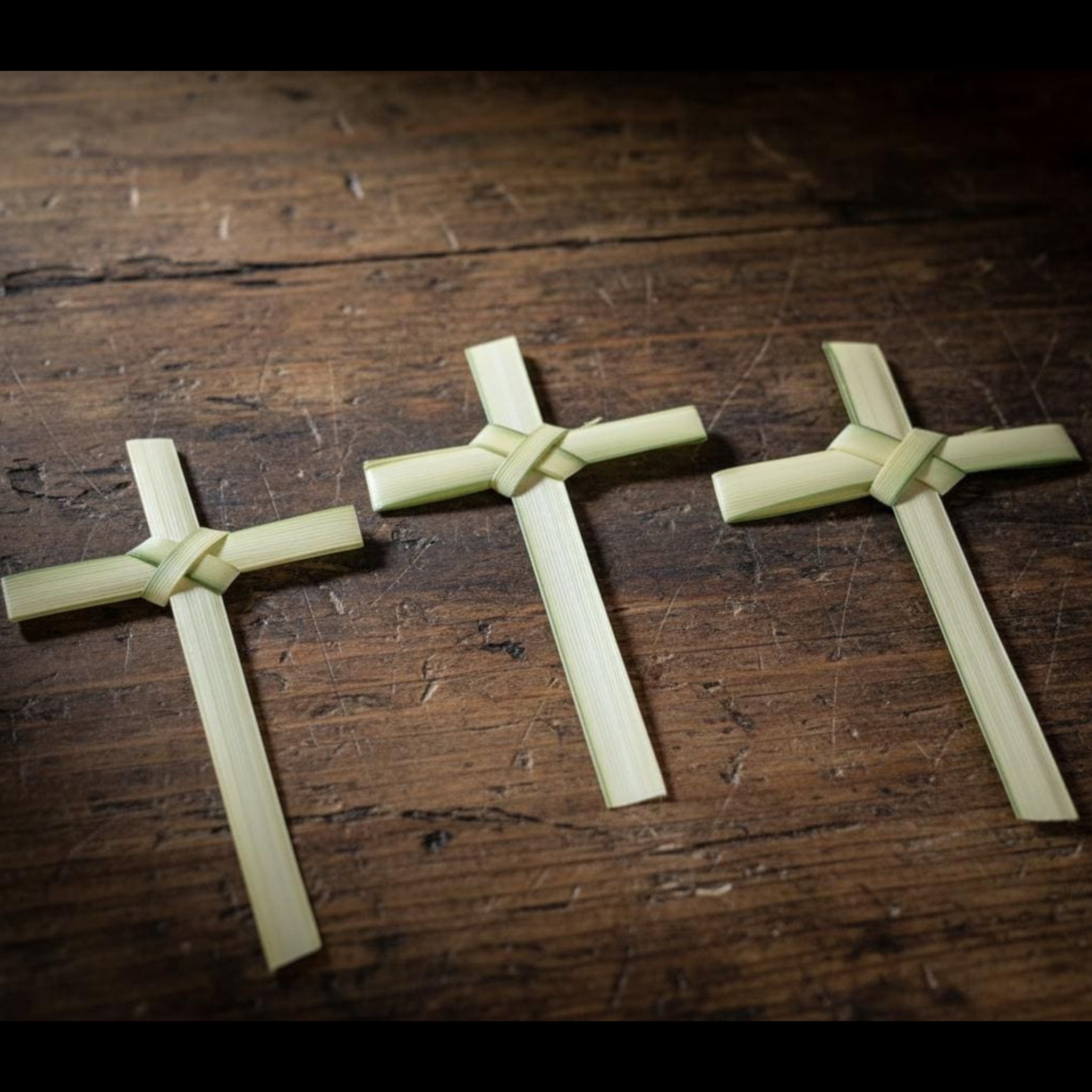Three wooden crosses on a rustic wooden surface