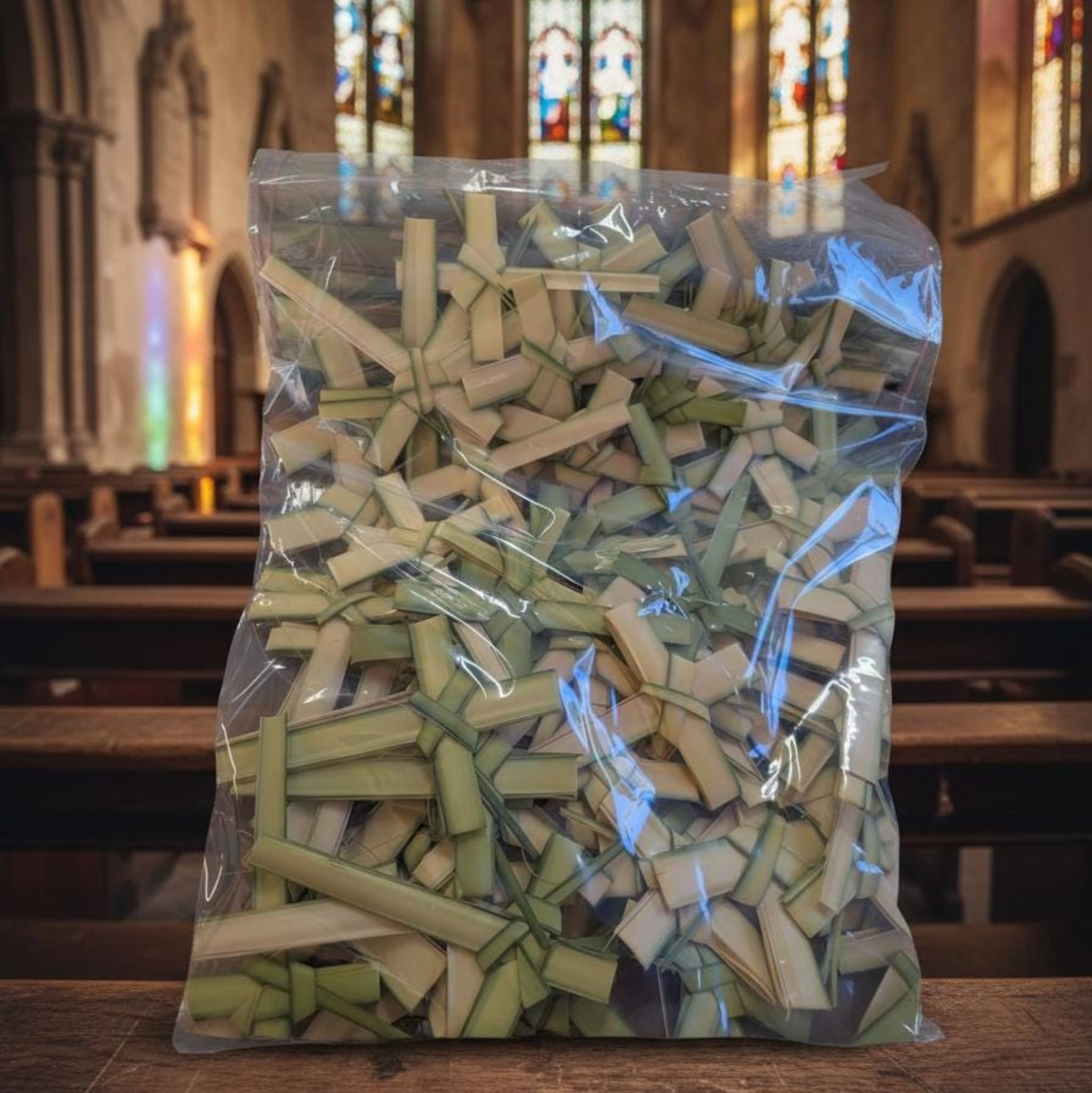 Bag of wooden crosses in a church setting with stained glass windows.