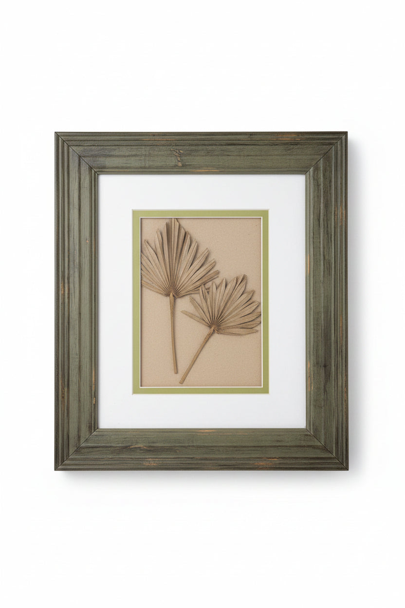 Framed artwork with a palm leaf design on a plain background
