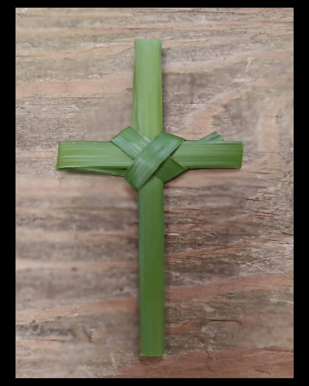 Green hand folded Cross on a wooden surface